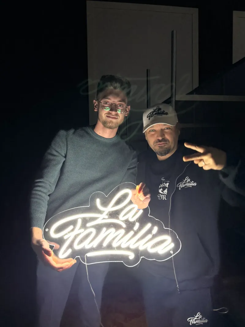 Clienți ținând semnul neon La Familia